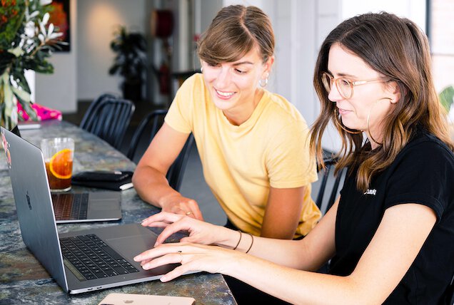 Two female franchise owners using franchise booking system on laptop.